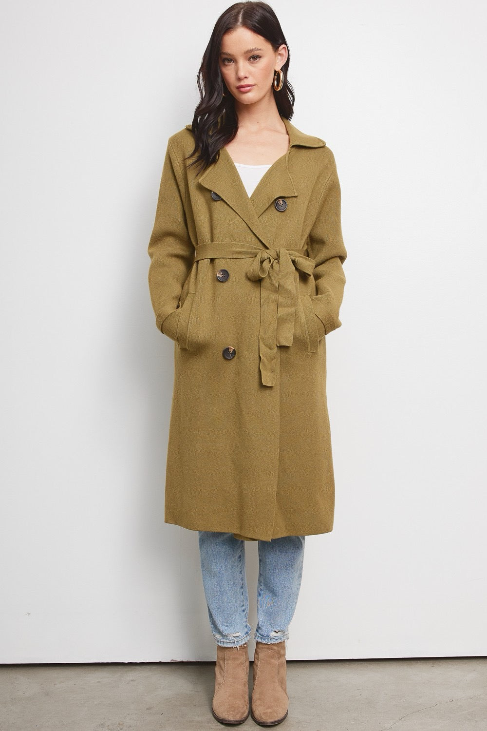Model wearing a Trestles Clothing Company Beckham midi sweater coat in olive green with a belted waist and buttons.