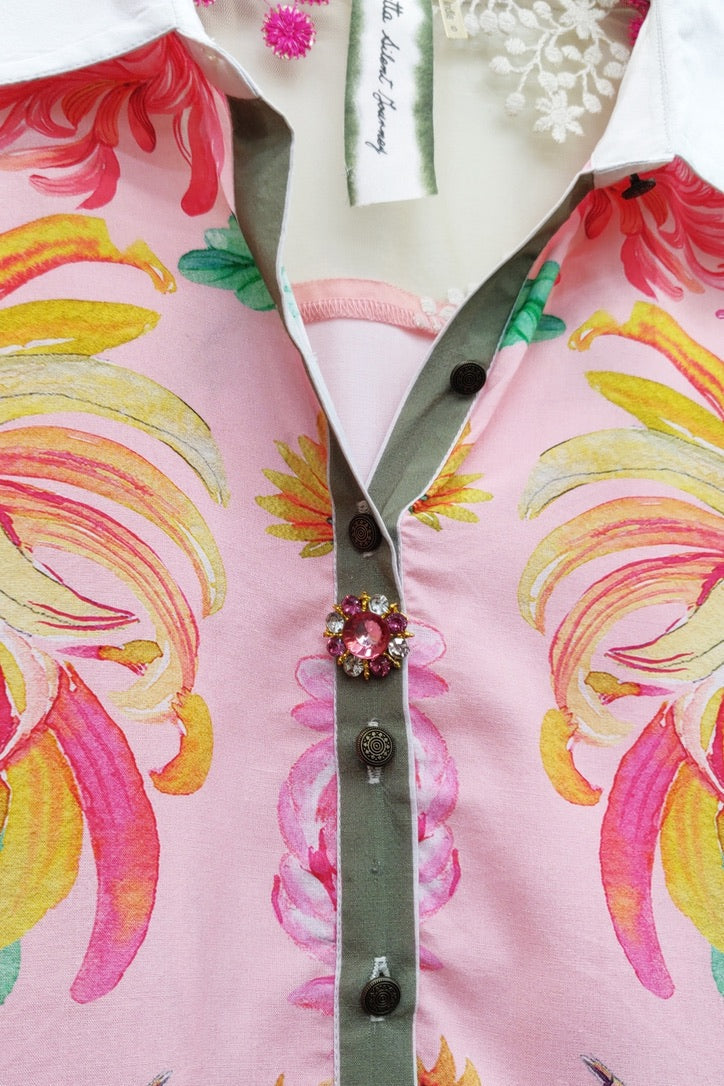 Trestles Clothing Company pink viscose blouse with crane print, white collar, and decorative jeweled button detail.