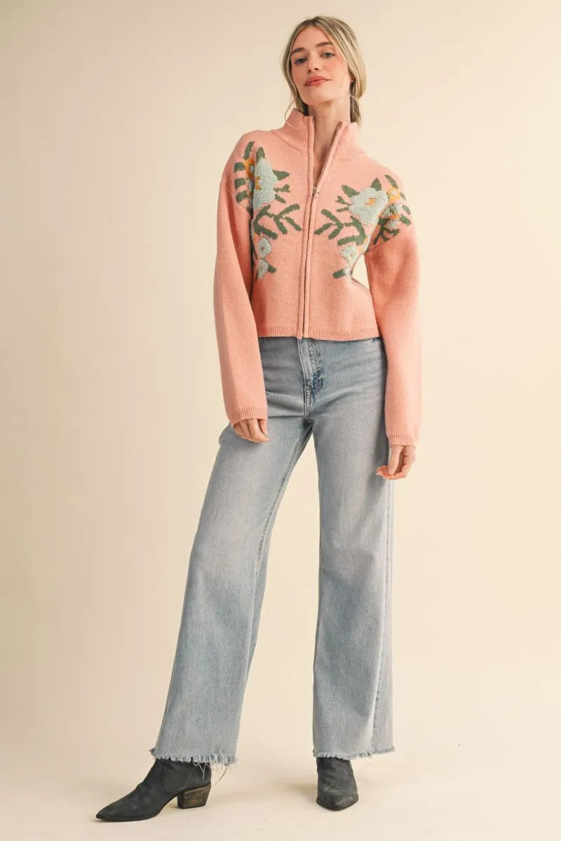 Trestles Clothing Company pink floral knit zip-up sweater with long puff sleeves and stand collar on a model