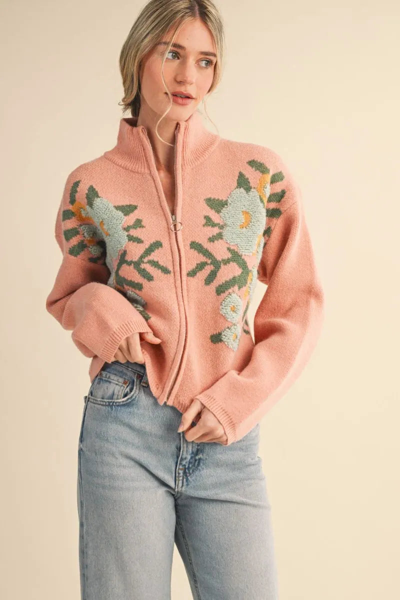 Trestles Clothing Company floral zip up knit sweater in pink with puff sleeves and stand collar on a model