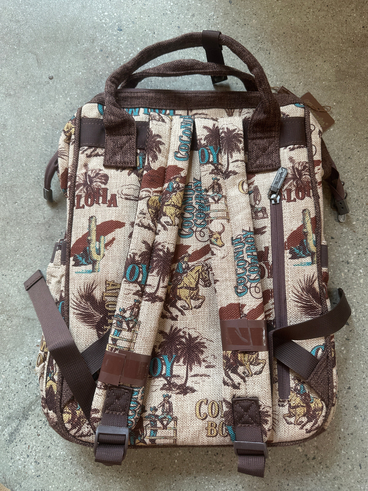 Trestles Clothing Company retro cowboy canvas backpack with vintage Western print, brown straps, and back zip pocket