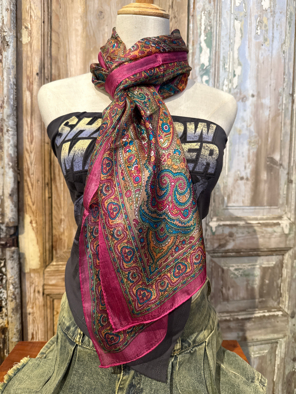 Trestles Clothing Company silk boho scarf featuring vibrant paisley prints in pink, teal, and gold on a mannequin.