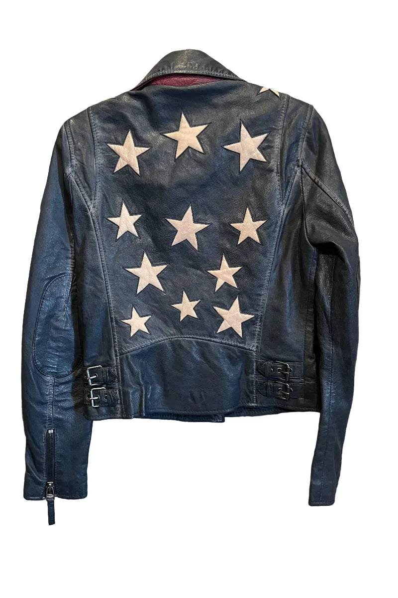 Trestles Clothing Company black lamb leather jacket with a back star design and side buckles hanging on a rustic door.