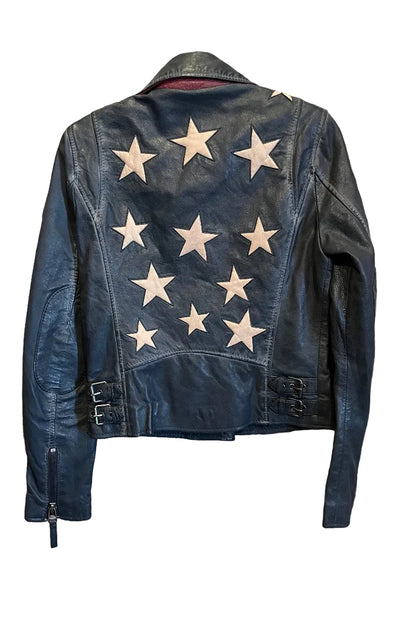 Trestles Clothing Company black lamb leather jacket with a back star design and side buckles hanging on a rustic door.