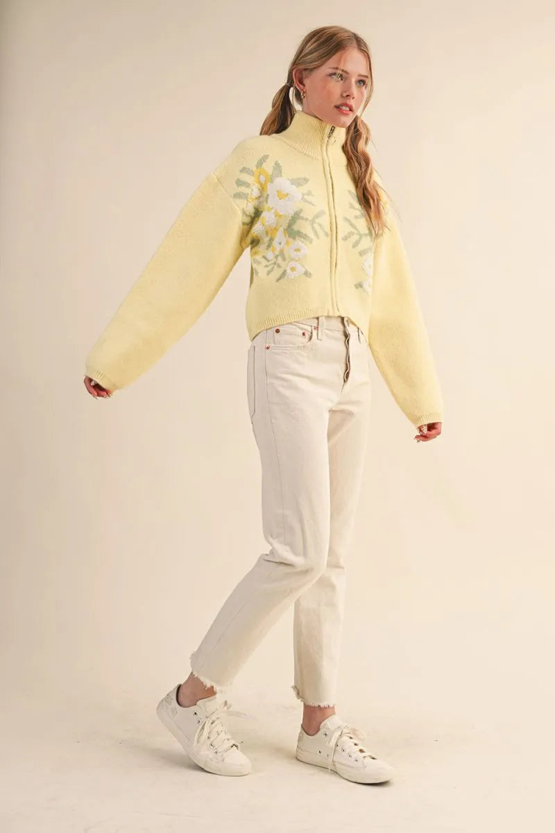 Trestles Clothing Company floral zip-up sweater in pale yellow with puff sleeves and a cropped, retro-inspired fit.