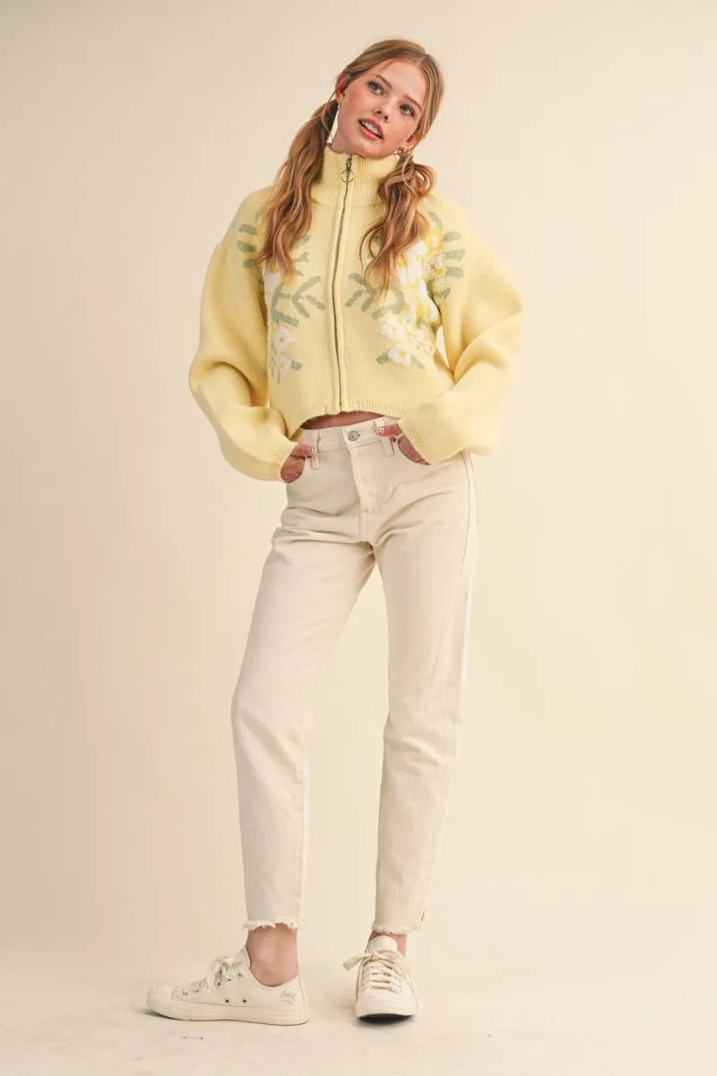 Trestles Clothing Company yellow floral knit zip-up sweater with puff sleeves worn by a model with cream jeans